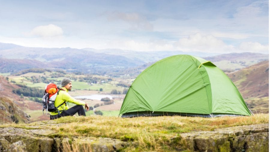 man sitting next to camping tent