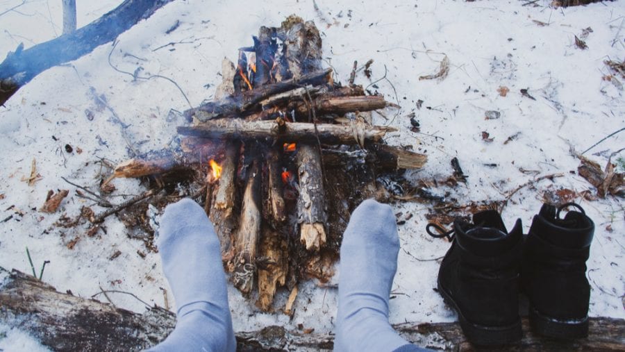 man wearing winter heated socks against the bonfire
