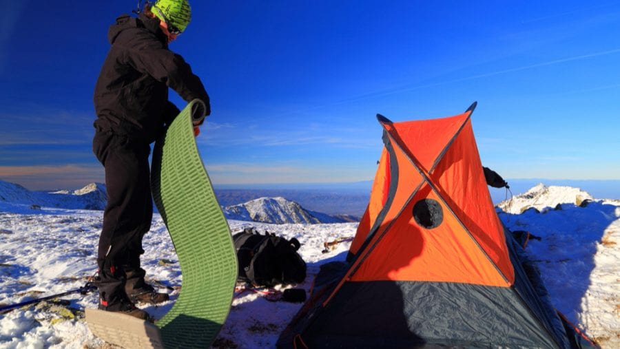 man with green sleeping pad during winter camp