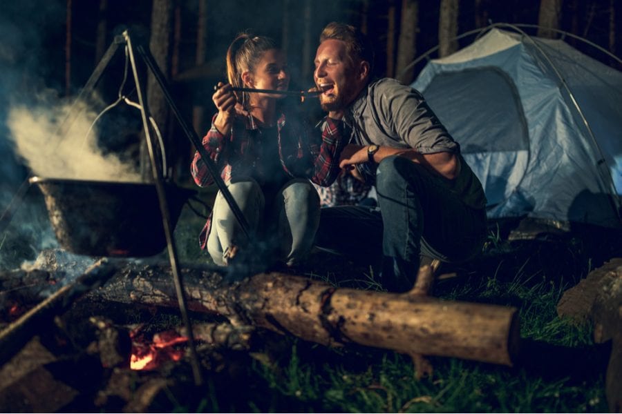 Couple cooking a romantic camping dinner