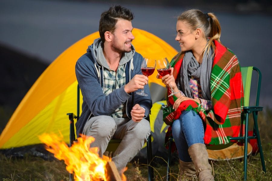 Romantic couple near a fire while camping and drinking wine