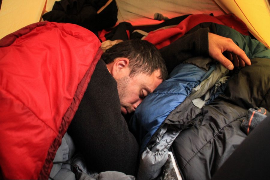tourist sleeping inside tent with camping gears all around